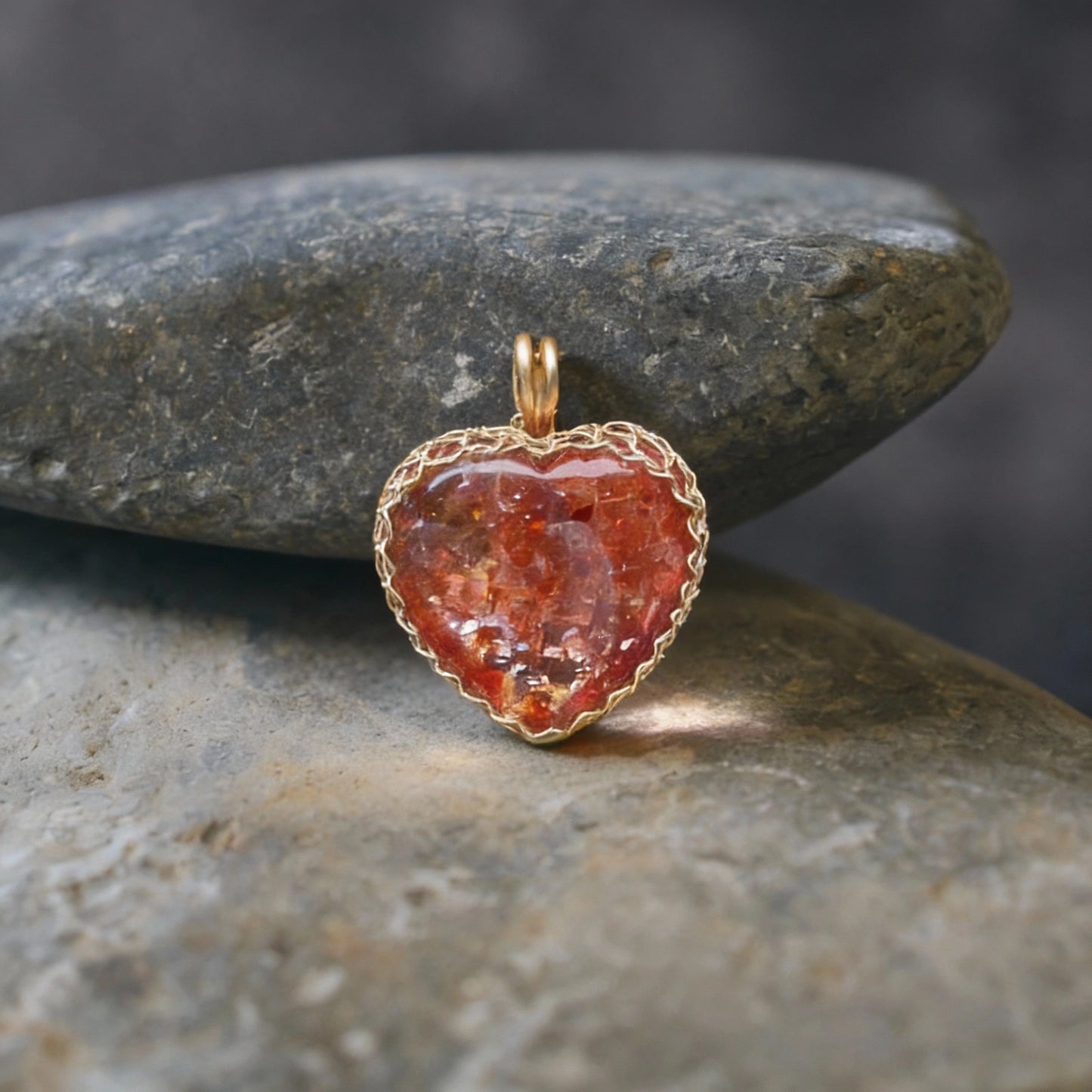 Pendant standing upright on smooth gray river stones.
