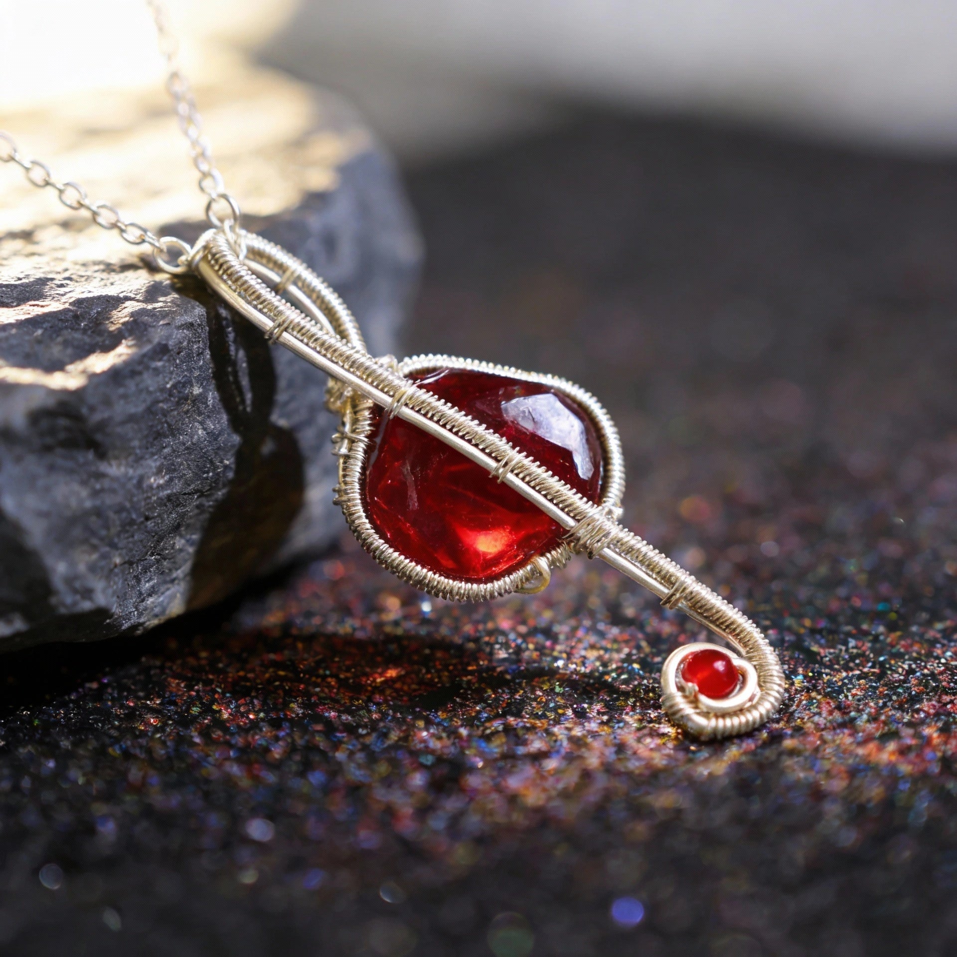 Pendant leaning on a gray stone with glittered surface below, close-up.