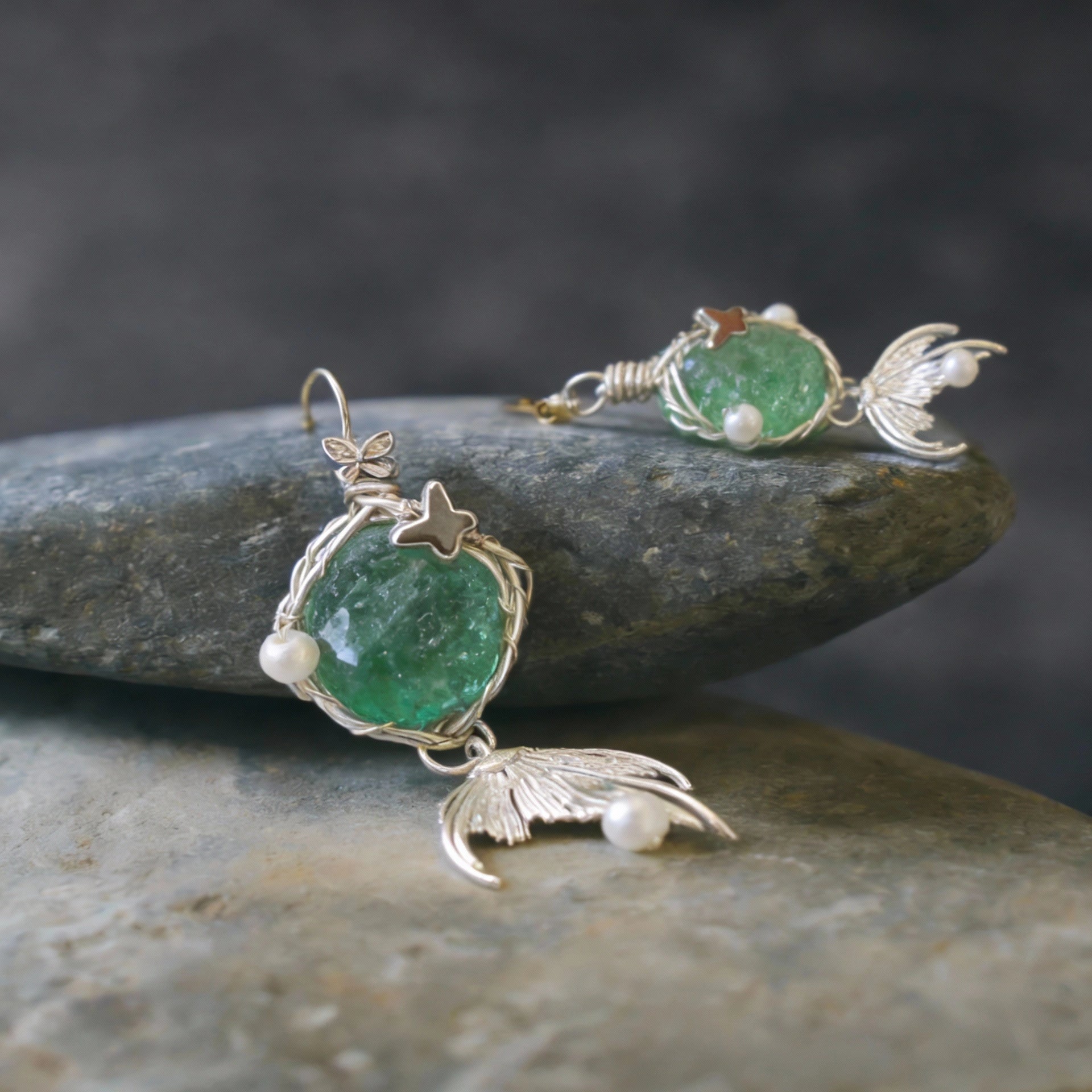 The pendant resting on stacked smooth stones, side view.