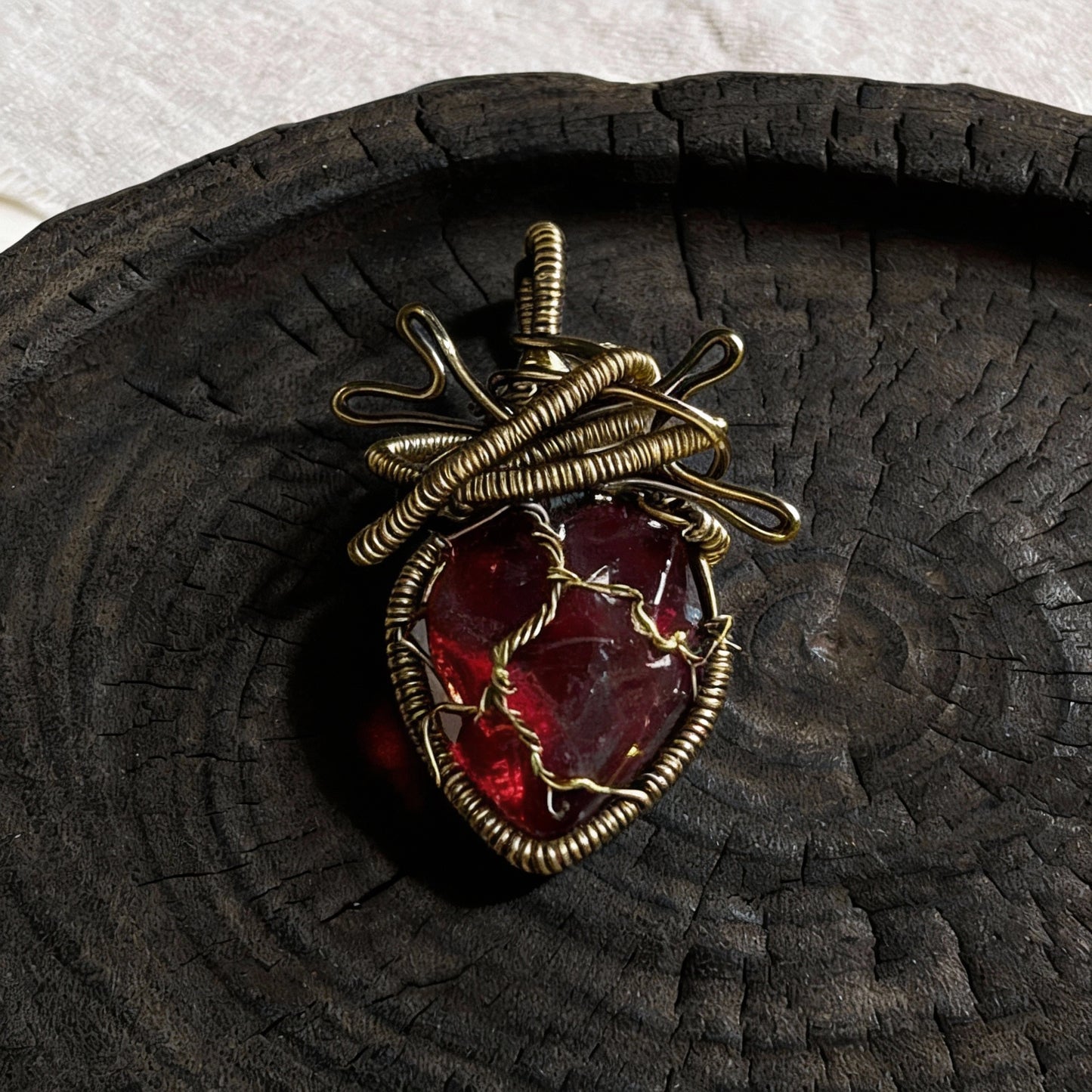 Pendant laid on a dark wooden plate, top-down view.