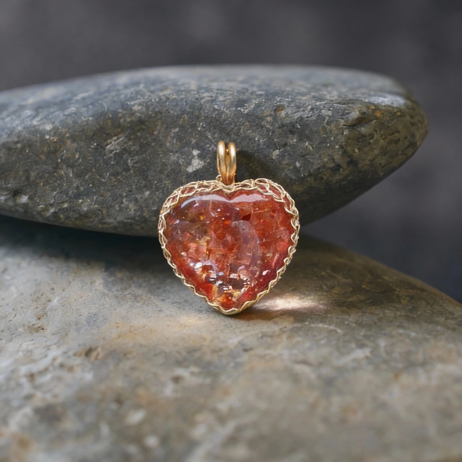 Pendant standing upright on smooth gray river stones.