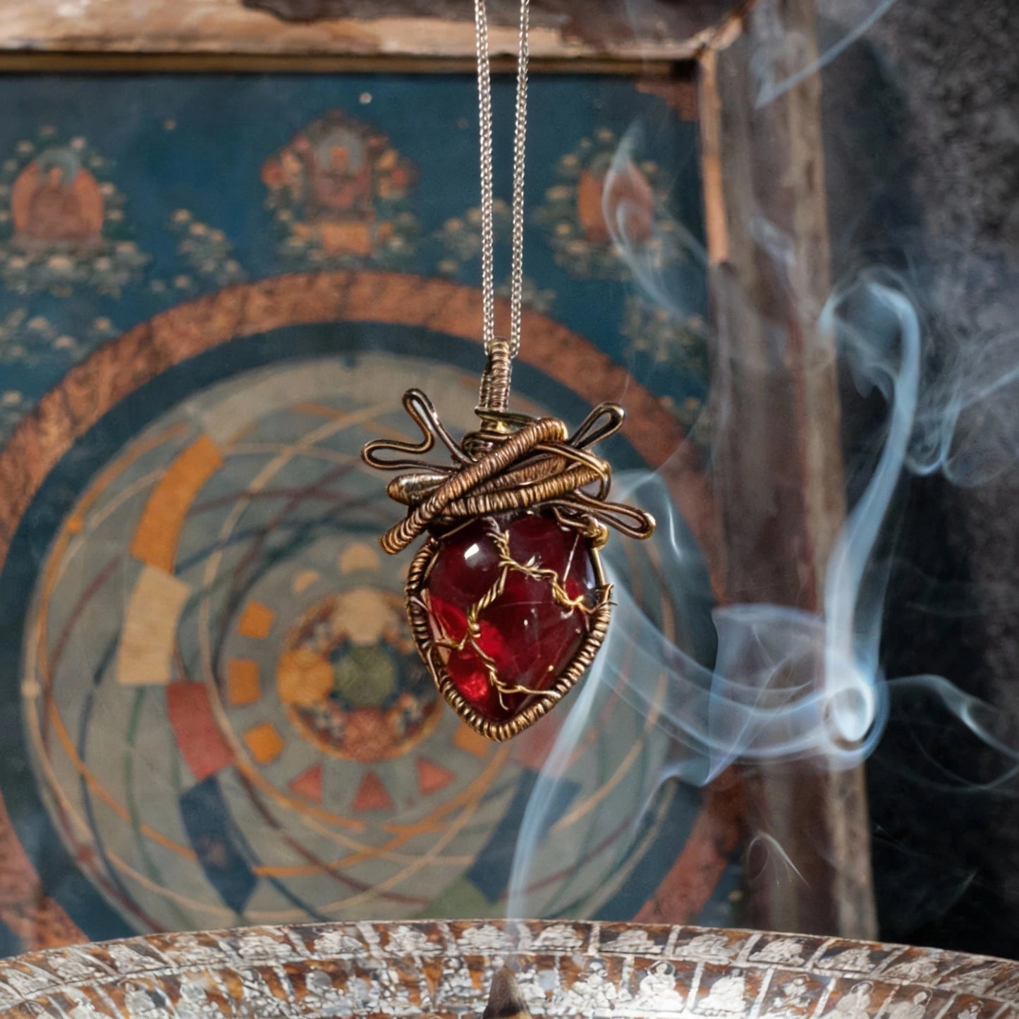Pendant suspended above an incense burner with ornate backdrop and smoke.