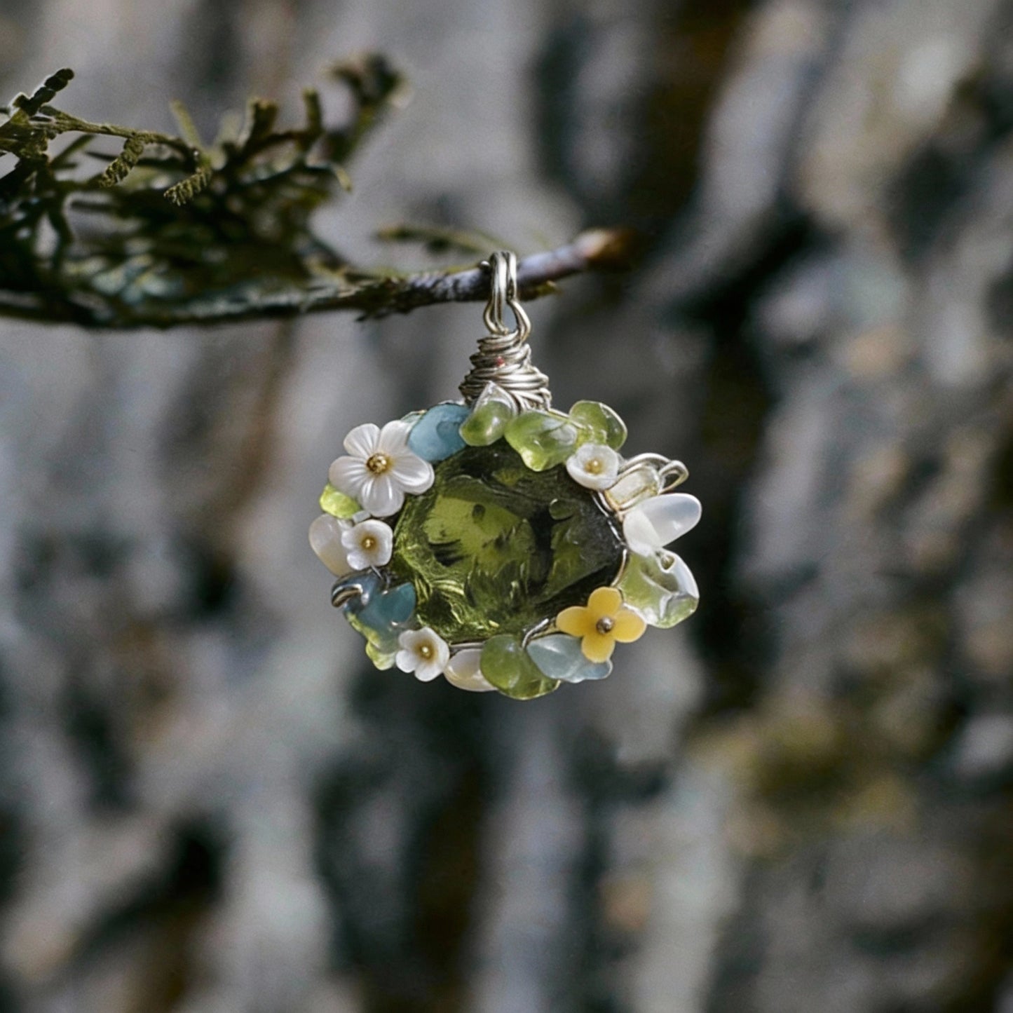 Pendant hanging from a small branch against tree-bark background.