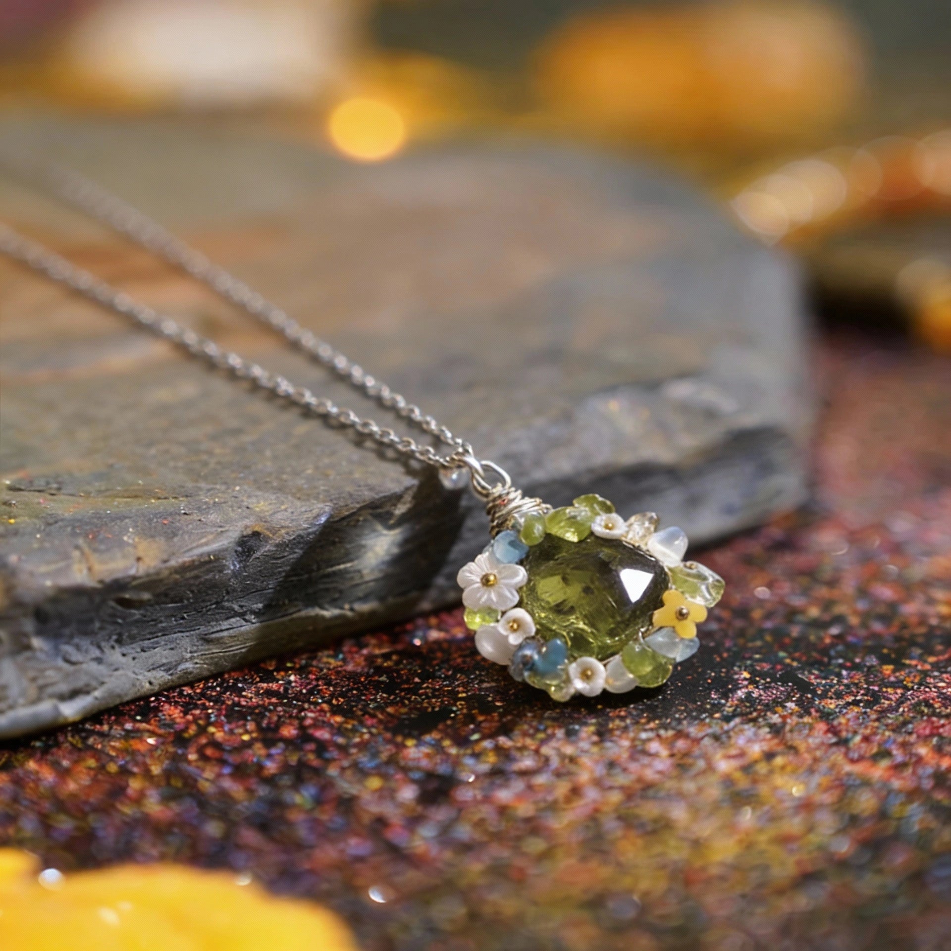 The same pendant resting on a textured surface with warm bokeh lights.