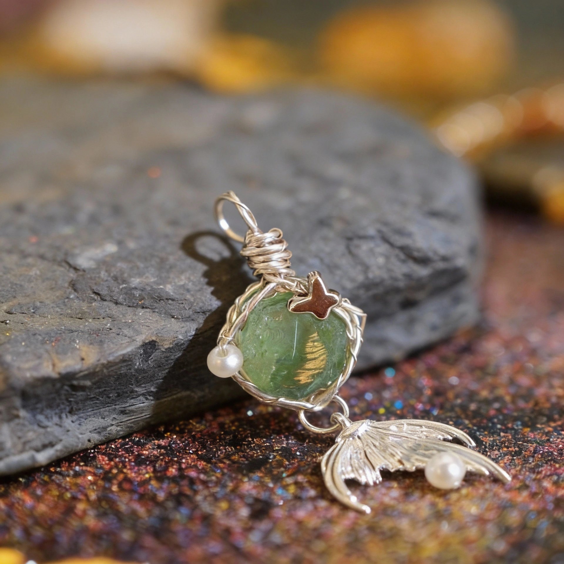 Pendant lying on a textured surface with warm bokeh lights, small dangle visible.