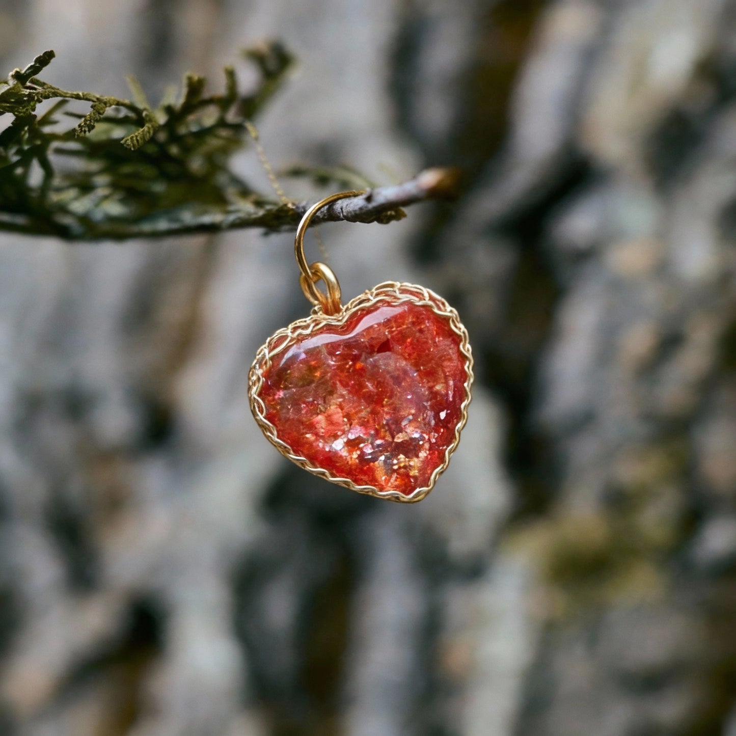 Pendant hanging from a branch in front of a tree-bark background.