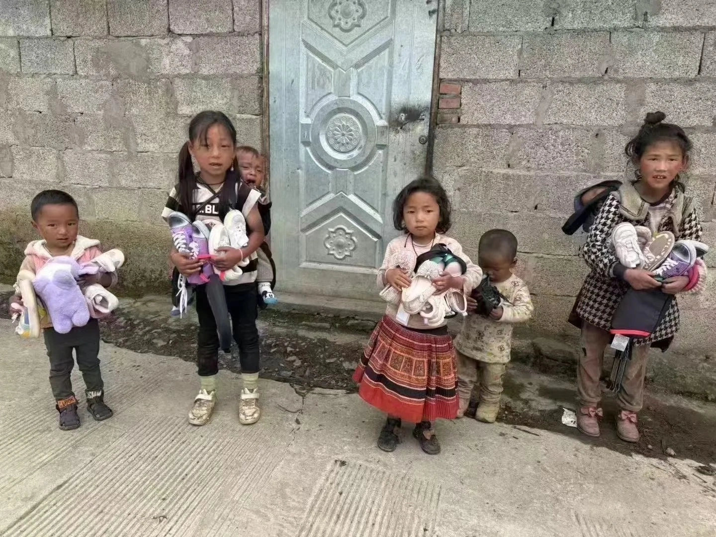 Children in a rural village hold donated shoes—supported by our handmade crystal pendant, wire‑wrapped necklace, boho spiritual jewelry, and talisman amulet gifts.