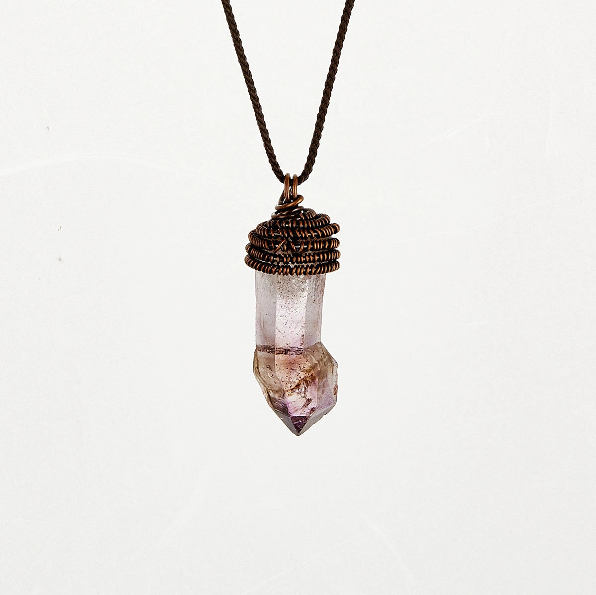 Single amethyst pendant on a cord against a plain light background.