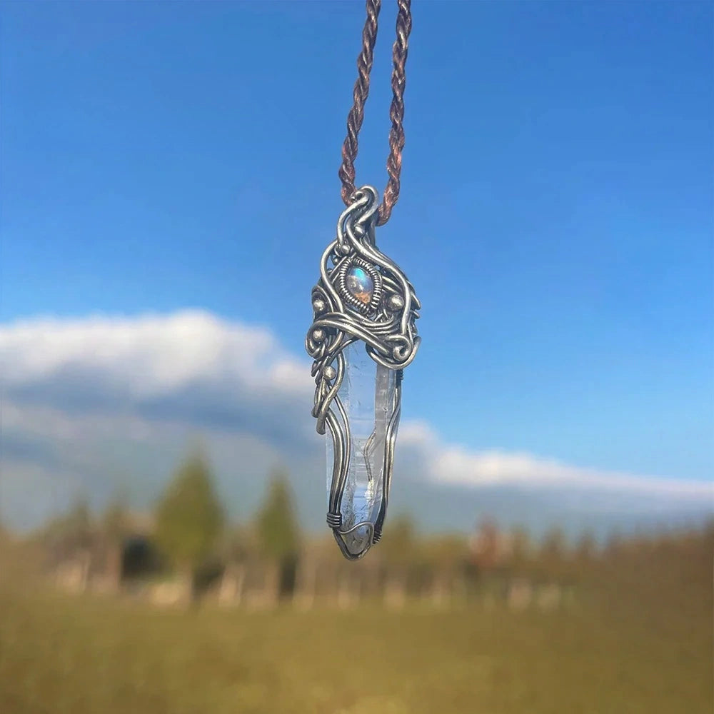 Pendant hanging outdoors with blurred grass and trees in the background.