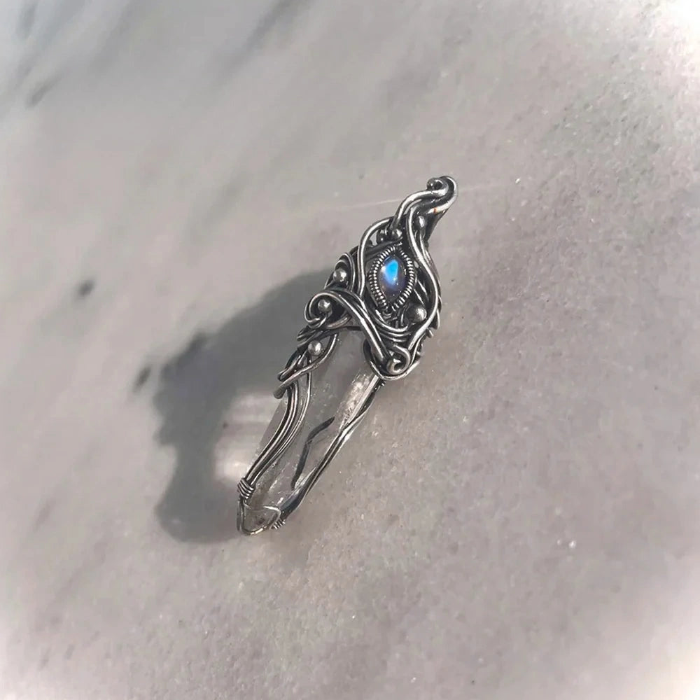 Pendant laid on pale sand or stone surface, soft shadows.