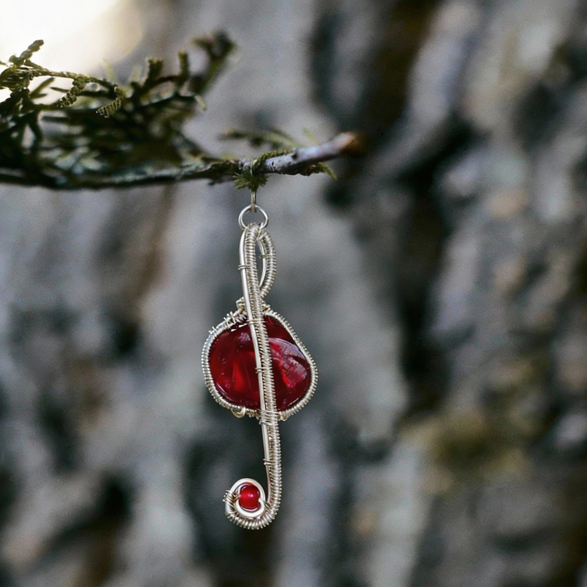 Pendant hanging from a small branch against a tree-bark background.