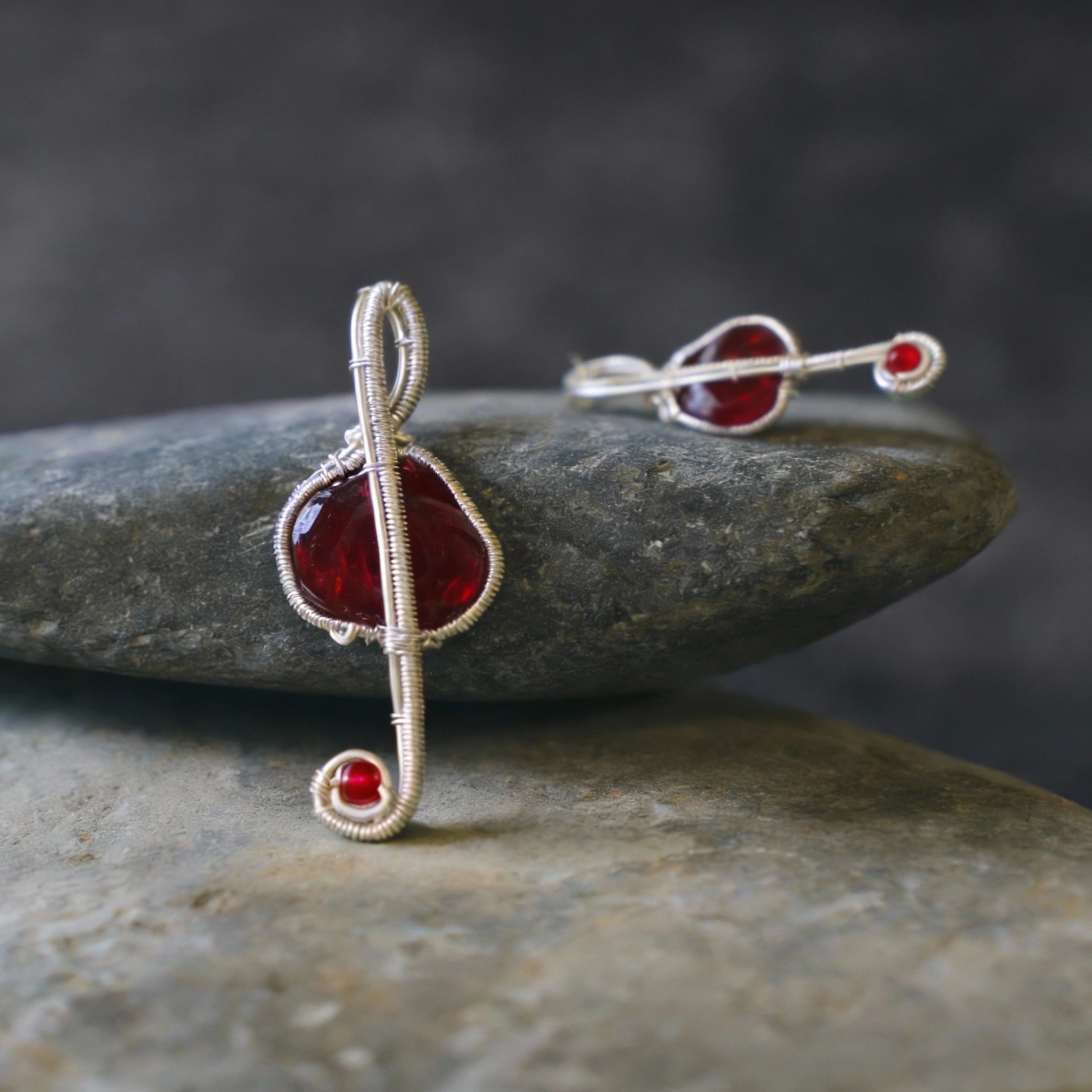 Pendant laid across stacked smooth stones, side angle.